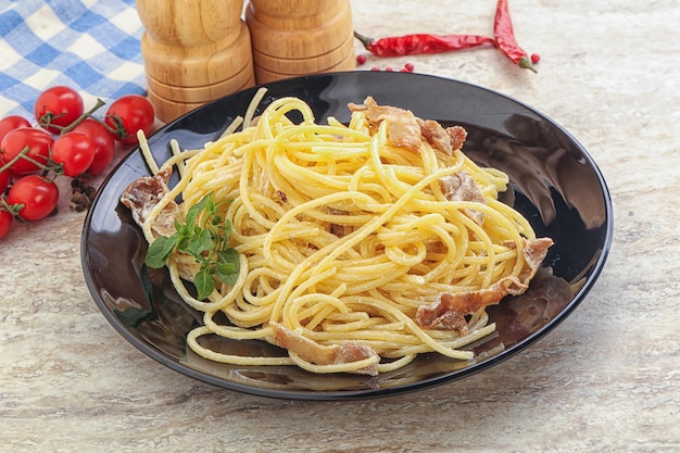 Spaghetti Carbonara pasta met spek geserveerd met basilicumblaadjes