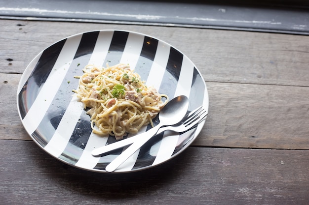 Spaghetti carbonara on white and black bowl