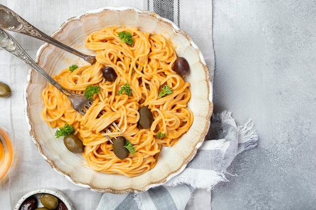 Spaghetti in creamy tomato sauce with olives and Parmesan