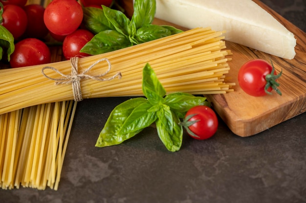 Spaghetti on a dark background, cheese, tomatoes, and basil