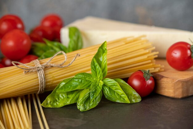 Spaghetti on a dark background, cheese, tomatoes, and basil