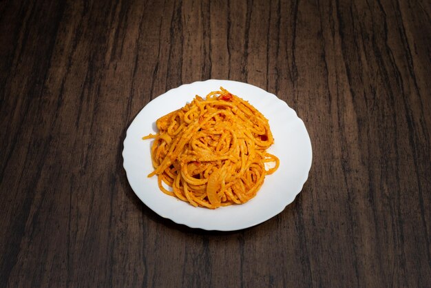 Spaghetti dish served in white plate on wooden table