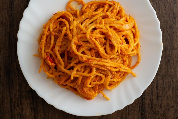 Spaghetti dish served in white plate on wooden table