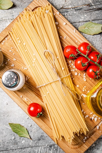 Spaghetti droog op een houten snijplank met tomaten