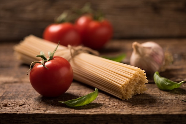 Spaghetti en tomaten met kruiden op een oude en vintage houten tafel