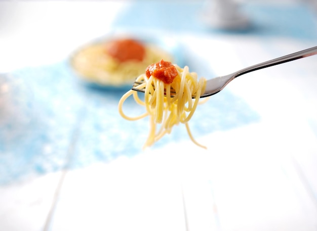 Photo spaghetti on a fork with tomato sauce.