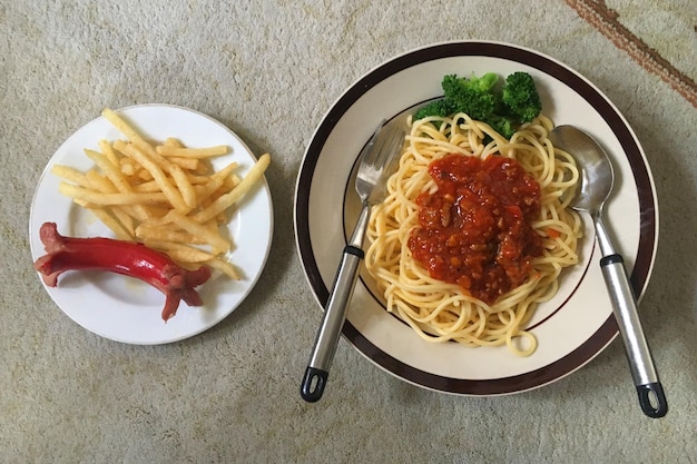 Spaghetti and french fries and a sausage