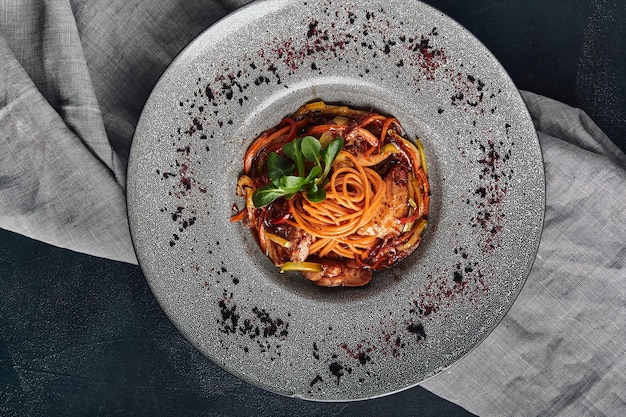 Spaghetti fried tomato and eggplant on over a dark slate, stone or concrete background. Top view with copy space. Food photo, traditional italian food.