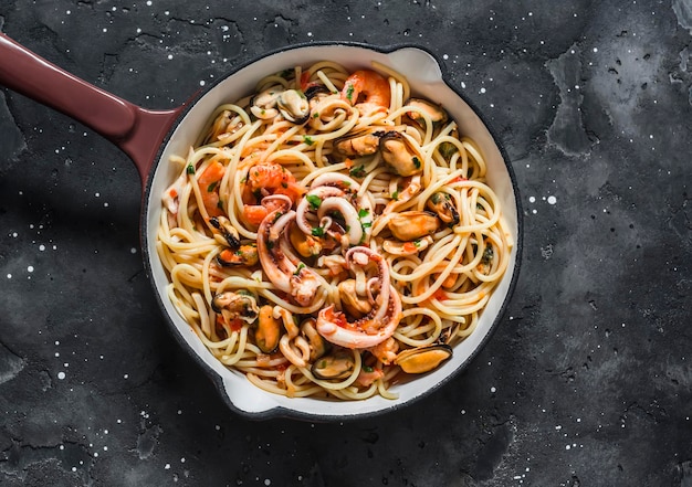 Spaghetti frutti di mare in cooking pan on a dark background top view Delicious traditional mediterranean food