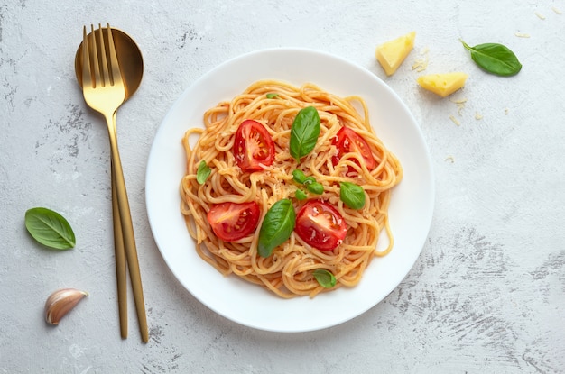 Spaghetti in tomatensaus met kaas op een witte plaat op een lichte ruimte