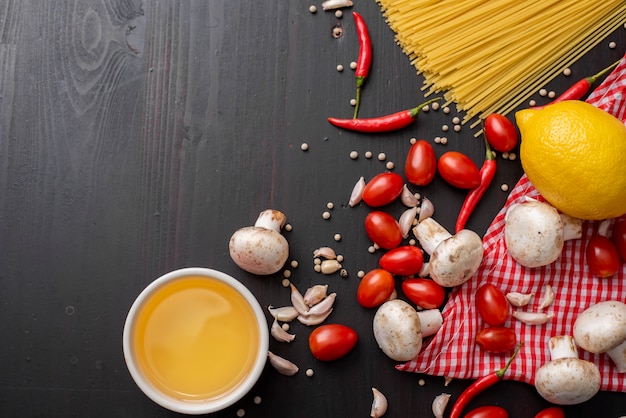 Spaghetti ingredients on black wooden desk, top view.