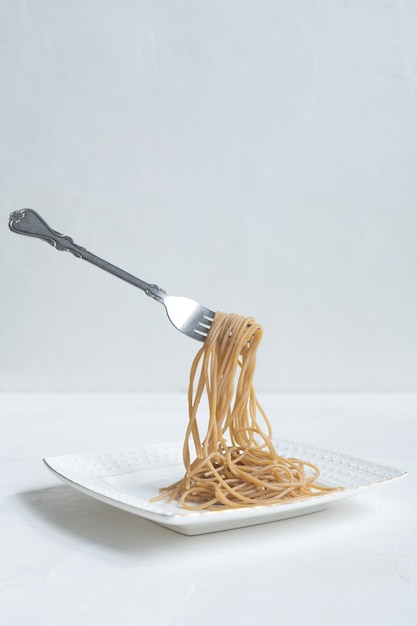 Spaghetti made from buckwheat on a white table.