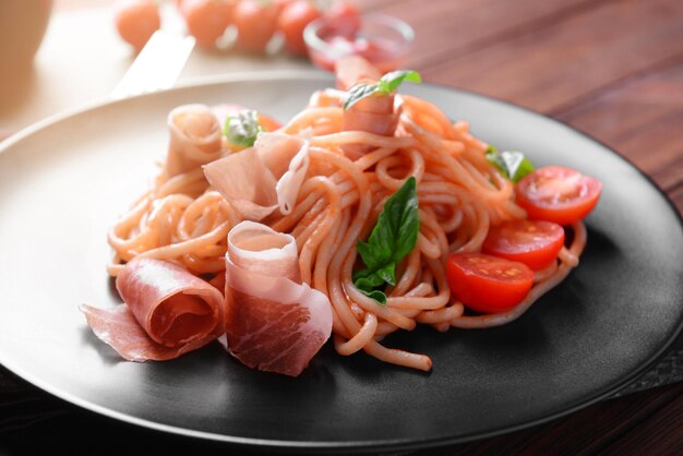 Foto spaghetti met amatricianasaus en bacon op zwarte plaatclose-up