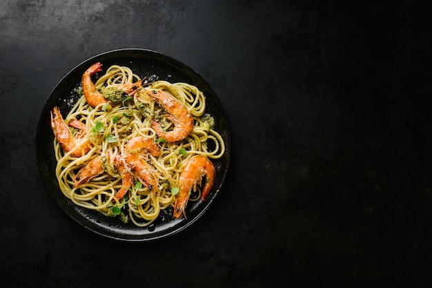 Spaghetti met pesto en garnalen die op plaat worden gediend