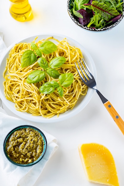Spaghetti met pestosaus en basilicum op een witte achtergrond. Pasta met saus pesto en ingrediënten