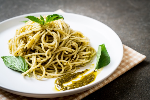 spaghetti met pestosaus, olijfolie en basilicumbladeren.