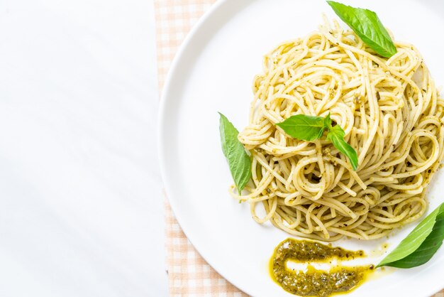 spaghetti met pestosaus, olijfolie en basilicumbladeren.