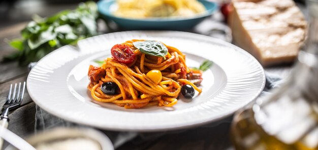 Spaghetti met rode saus, tomaten, olijven, basilicum en olijfolie.