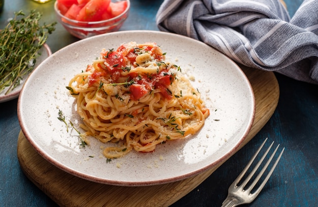 Spaghetti met tomaten en tijm in een bord op een blauwe tafel