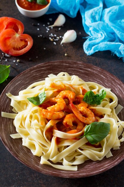 Spaghetti met tomatensaus en garnalen in een bord op donkere betonnen steen of leisteen achtergrond