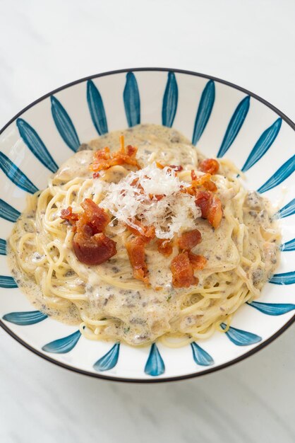 spaghetti met truffelroomsaus en champignon op bord