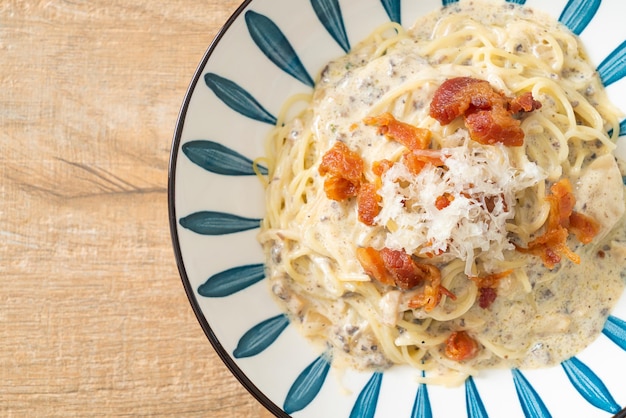 spaghetti met truffelroomsaus en champignon op bord