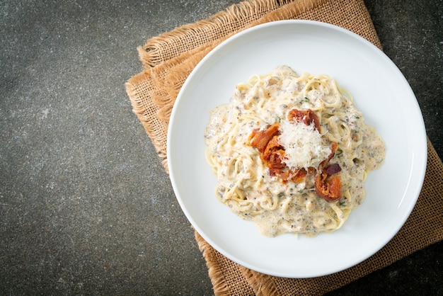 spaghetti met truffelroomsaus en champignon op bord