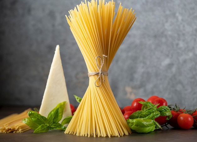 Spaghetti op een donkere ondergrond, kaas, tomaten en basilicum