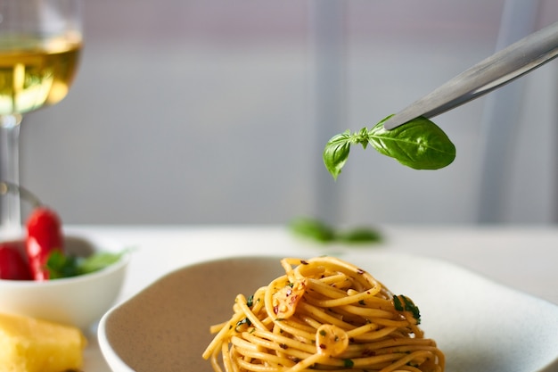 Макароны спагетти aglio e olio с хлопьями чили, петрушкой и чесноком, украшенные базиликом