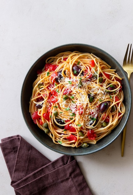 Spaghetti pasta Alla Puttanesca met kappertjes Kalamata olijven kaas tomaten en ansjovis Italiaans eten