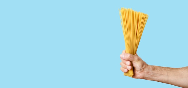 Spaghetti pasta in hand on a blank banner background raw italian spaghetti before cooking and eating...
