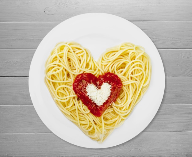 Spaghetti pasta in hartvorm op tafel.