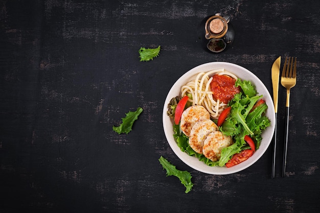 Spaghetti pasta kipburgers en salade in kom Kippasteitjes Lunch Bovenaanzicht boven kopieerruimte