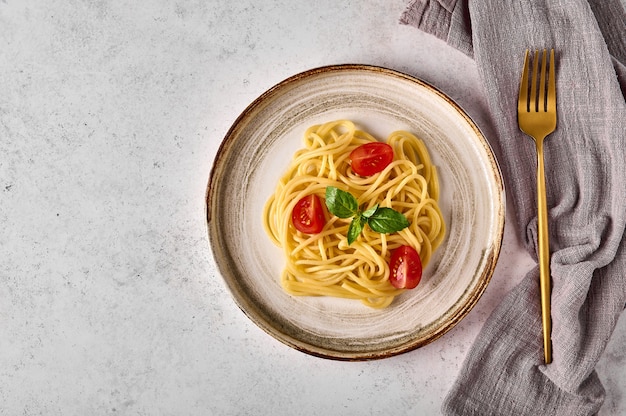 Spaghetti pasta met tomaat cherry Parmezaanse kaas en basilicum op keramische plaat met vork en servet