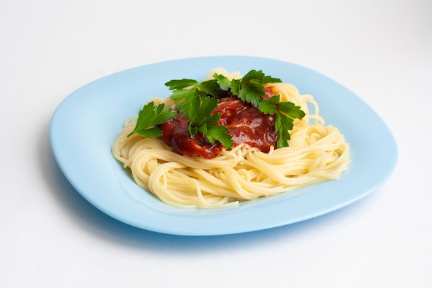 Spaghetti pasta met tomatensaus en kruiden in een blauw bord op wit