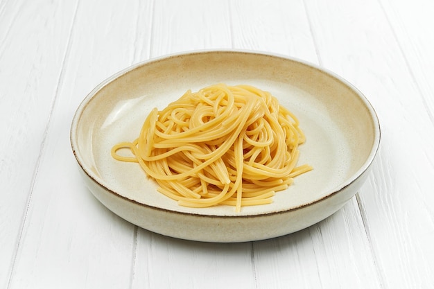 Photo spaghetti pasta in a plate on a white wooden background