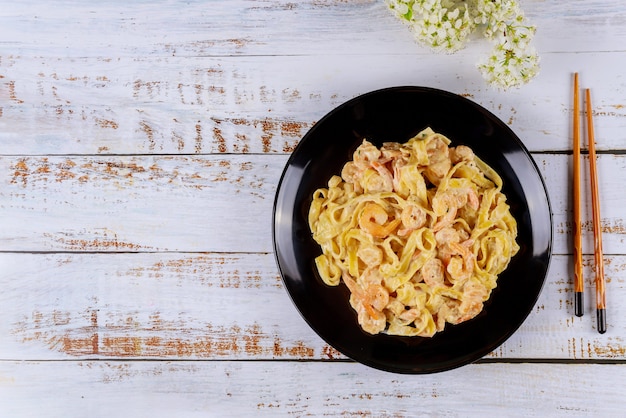 Spaghetti pasta with alfredo sauce and shrimps in black plate.