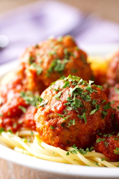 Spaghetti pasta with meatballs in tomato sauce and herbs on a white plate