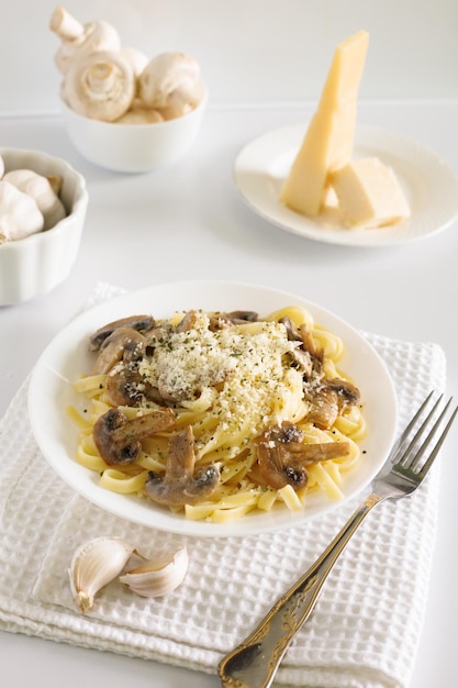 spaghetti pasta with mushrooms and parmesan cheese in a creamy sauce on a white table