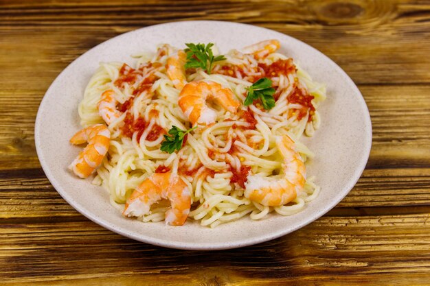 Паста спагетти с креветками, томатным соусом и петрушкой на деревянном столе