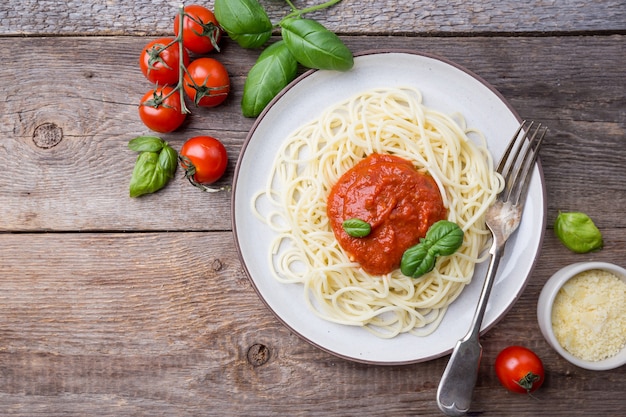 Spaghetti pasta with tomato sauce and basil over wooden