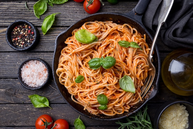 Foto pasta degli spaghetti con salsa di pomodoro e basilico su legno