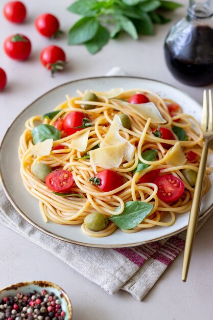 トマト、バジル、オリーブ、パルメザンチーズのスパゲッティパスタ。健康的な食事。ベジタリアンフード。