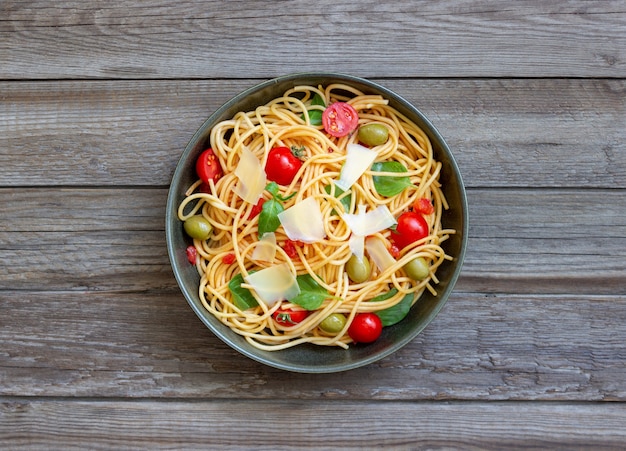 Spaghetti pasta with tomatoes, basil, olives and Parmesan cheese. Healthy eating. Vegetarian food.
