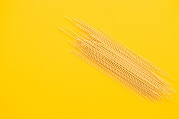 Spaghetti pasta on yellow background from above