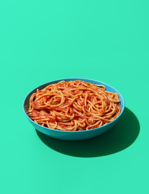 Foto piatto di spaghetti pomodoro isolato su uno sfondo verde