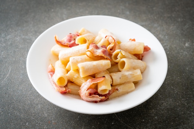 Spaghetti rigatoni pasta with white sauce and bacon