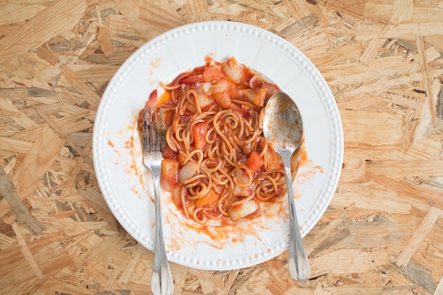 Спагетти-морепродукты с саловым соусом в белой тарелке на деревянном столе в столовой