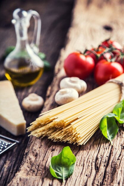 Foto spaghetti pomodoro basilico olio d'oliva parmigiano e funghi su tavola di quercia molto vecchia