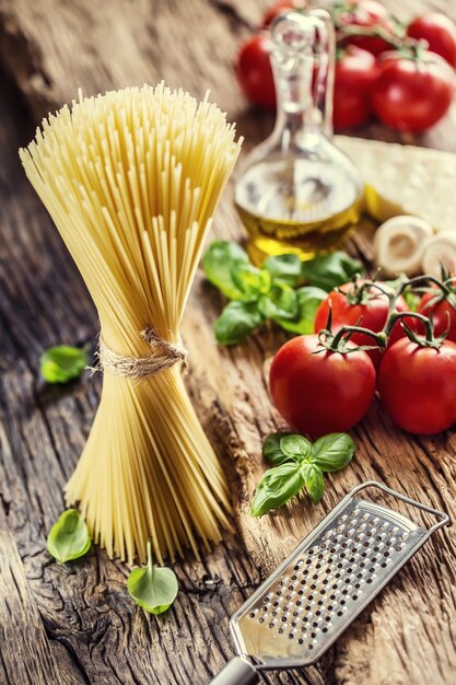 Spaghetti tomatoes basil olive oil parmesan cheese and mushrooms on very old oak board